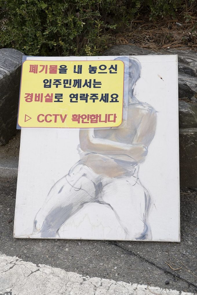 An unfinished painting beneath a waste-warning sign